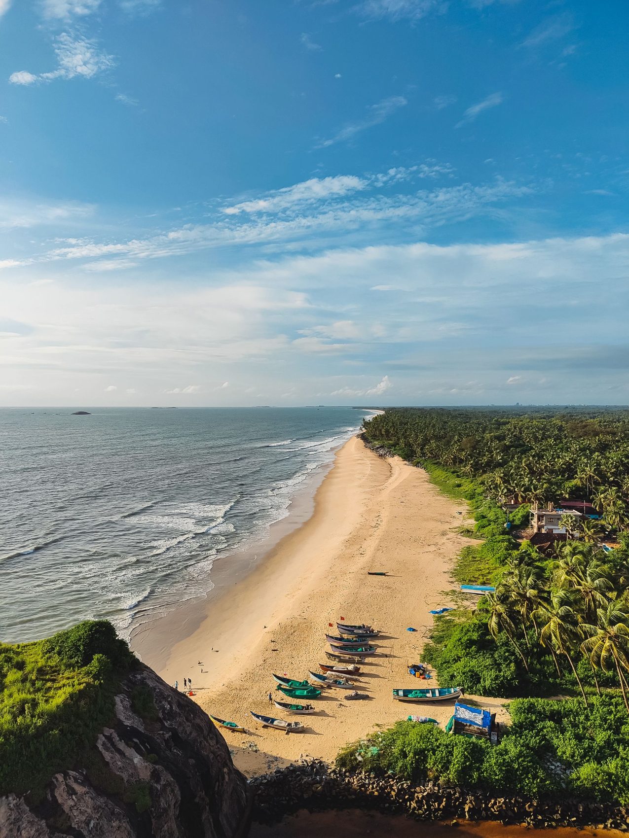 Aerial view of a golden Kundapura beach with fishing boats and palm trees